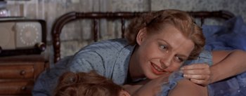 Movie still from “Picnic” (1955), directed by Joshua Logan – A person laying on a bed with a baby; Close Up shot, Over the shoulder angle