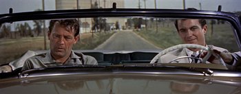 Movie still from “Picnic” (1955), directed by Joshua Logan – Two men in the back of a car looking out the window; Medium shot, Over the shoulder angle