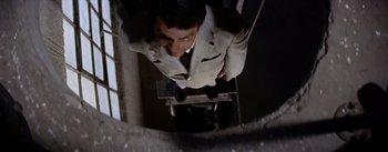 Movie still from “Picnic” (1955), directed by Joshua Logan – A man in a suit and tie standing on top of a ladder; Medium shot, Overhead angle