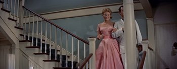 Movie still from “Picnic” (1955), directed by Joshua Logan – A man and a woman in a pink dress and white suit; Medium shot, Low angle