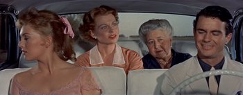 Movie still from “Picnic” (1955), directed by Joshua Logan – A group of people sitting in a car; Medium shot, Over the shoulder angle