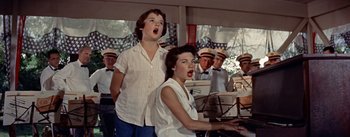 Movie still from “Picnic” (1955), directed by Joshua Logan – Two young women singing in front of an audience; Medium shot, Low angle