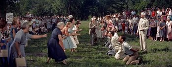 Movie still from “Picnic” (1955), directed by Joshua Logan – A group of people standing in the grass near trees; Wide shot, High angle