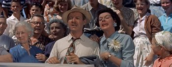 Movie still from “Picnic” (1955), directed by Joshua Logan – An older man and woman sing together in front of a crowd; Medium shot, Low angle