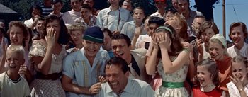 Movie still from “Picnic” (1955), directed by Joshua Logan – A group of people that are standing in the grass; Medium shot, High angle