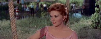 Movie still from “Picnic” (1955), directed by Joshua Logan – A woman in a pink dress is looking at the camera; Close Up shot, Over the shoulder angle