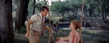 Movie still from “Picnic” (1955), directed by Joshua Logan – A man and a woman in a field with trees in the background; Medium shot, Over the shoulder angle