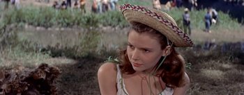 Movie still from “Picnic” (1955), directed by Joshua Logan – A young woman wearing a straw hat in a grassy area; Close Up shot, High angle