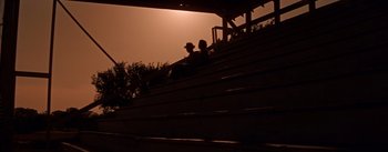 Movie still from “Picnic” (1955), directed by Joshua Logan – Two people sitting on bleachers at a football game; Extreme Wide shot, Low angle