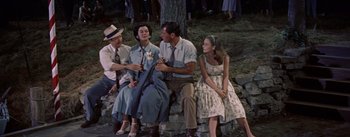 Movie still from “Picnic” (1955), directed by Joshua Logan – A group of people sitting next to each other on a stone wall; Medium shot, High angle