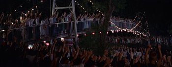 Movie still from “Picnic” (1955), directed by Joshua Logan – A group of people standing on a stage with their hands up; Extreme Wide shot, High angle