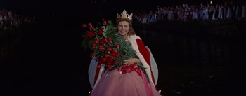Movie still from “Picnic” (1955), directed by Joshua Logan – A woman dressed as a queen holding a bouquet of roses; Medium shot, High angle