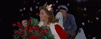 Movie still from “Picnic” (1955), directed by Joshua Logan – A woman dressed as a queen holding a bouquet of roses; Medium shot, High angle