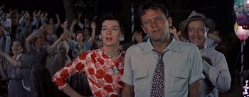 Movie still from “Picnic” (1955), directed by Joshua Logan – An older woman standing next to an older man in front of a crowd; Close Up shot, Low angle