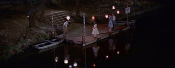 Movie still from “Picnic” (1955), directed by Joshua Logan – A group of people standing next to a body of water at night; Extreme Wide shot, High angle