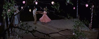 Movie still from “Picnic” (1955), directed by Joshua Logan – A man and a woman in a pink dress dancing; Wide shot, High angle