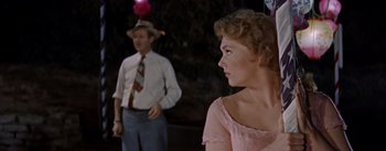 Movie still from “Picnic” (1955), directed by Joshua Logan – A man and a woman standing next to each other in front of balloons; Close Up shot, Over the shoulder angle