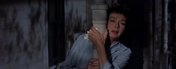Movie still from “Picnic” (1955), directed by Joshua Logan – A woman holding a white flower while standing next to a pillar; Close Up shot, Low angle