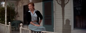 Movie still from “Picnic” (1955), directed by Joshua Logan – A woman sitting on the porch of a house; Medium shot, Low angle