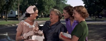 Movie still from “Picnic” (1955), directed by Joshua Logan – A group of women standing next to each other on the street; Medium shot, Over the shoulder angle