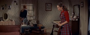 Movie still from “Picnic” (1955), directed by Joshua Logan – A woman standing in a living room reading a book; Medium shot, High angle