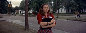 Movie still from “Picnic” (1955), directed by Joshua Logan – A young woman holding a book while standing on the side of the road; Medium shot, Low angle