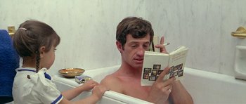 Movie still from “Pierrot le Fou” (1965), directed by Jean-Luc Godard – A man in a bath tub reading a book; Close Up shot, High angle