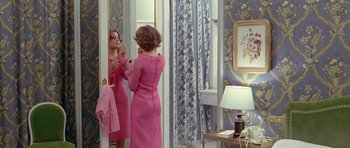 Movie still from “Pierrot le Fou” (1965), directed by Jean-Luc Godard – A woman in a pink dress looking in the mirror; Medium shot, Over the shoulder angle