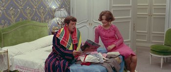 Movie still from “Pierrot le Fou” (1965), directed by Jean-Luc Godard – A man and a woman sitting on a bed looking at a magazine; Medium shot, High angle
