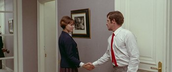 Movie still from “Pierrot le Fou” (1965), directed by Jean-Luc Godard – A man and a woman shaking hands in a room; Medium shot, Over the shoulder angle