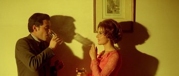 Movie still from “Pierrot le Fou” (1965), directed by Jean-Luc Godard – A woman in a pink dress smoking a cigarette; Medium shot, Low angle