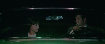 Movie still from “Pierrot le Fou” (1965), directed by Jean-Luc Godard – A woman and a man in a car at night; Medium shot, High angle