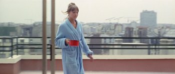 Movie still from “Pierrot le Fou” (1965), directed by Jean-Luc Godard – A woman in a blue bathrobe holding a red bowl; Wide shot, Low angle
