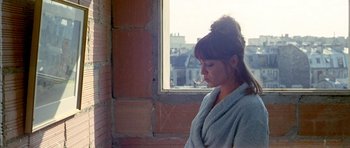 Movie still from “Pierrot le Fou” (1965), directed by Jean-Luc Godard – A woman in a bathrobe looking out of a window; Medium shot, Low angle