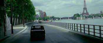 Movie still from “Pierrot le Fou” (1965), directed by Jean-Luc Godard – A car driving down a road next to a body of water; Extreme Wide shot, High angle