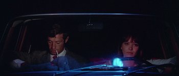 Movie still from “Pierrot le Fou” (1965), directed by Jean-Luc Godard – A man and a woman sitting in the back seat of a car; Medium shot, High angle