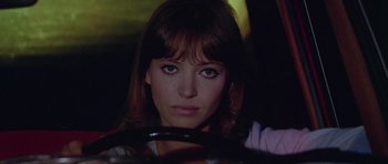 Movie still from “Pierrot le Fou” (1965), directed by Jean-Luc Godard – A woman sitting behind a steering wheel of a car; Close Up shot, Low angle