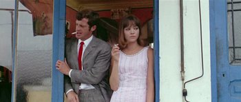 Movie still from “Pierrot le Fou” (1965), directed by Jean-Luc Godard – A man and a woman standing next to each other; Medium shot, Low angle