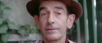 Movie still from “Pierrot le Fou” (1965), directed by Jean-Luc Godard – An older man wearing a hat and looking at the camera; Close Up shot, High angle