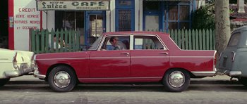 Movie still from “Pierrot le Fou” (1965), directed by Jean-Luc Godard – A man sitting in the driver's seat of a red car; Wide shot, High angle