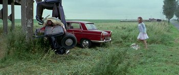 Movie still from “Pierrot le Fou” (1965), directed by Jean-Luc Godard – An old red car in the middle of a grassy field; Wide shot, High angle