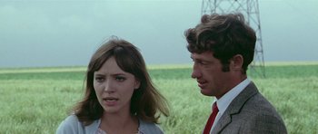 Movie still from “Pierrot le Fou” (1965), directed by Jean-Luc Godard – A man and a woman standing next to each other in a field; Close Up shot, Over the shoulder angle
