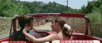 Movie still from “Pierrot le Fou” (1965), directed by Jean-Luc Godard – A man and a woman sitting in the back of a red car; Medium shot, High angle
