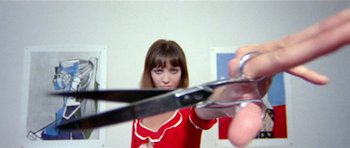 Movie still from “Pierrot le Fou” (1965), directed by Jean-Luc Godard – A woman holding a pair of scissors in front of a mirror; Extreme Close Up shot, Low angle