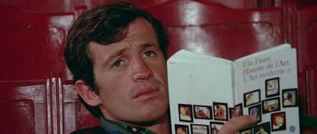 Movie still from “Pierrot le Fou” (1965), directed by Jean-Luc Godard – A person holding a book; Close Up shot, Low angle