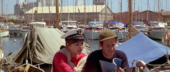 Movie still from “Pierrot le Fou” (1965), directed by Jean-Luc Godard – A man and a woman sitting on a dock; Medium shot, High angle