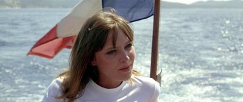 Movie still from “Pierrot le Fou” (1965), directed by Jean-Luc Godard – A woman in a white shirt is sitting on a boat; Close Up shot, Low angle
