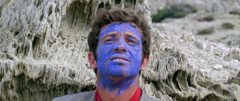 Movie still from “Pierrot le Fou” (1965), directed by Jean-Luc Godard – A man with blue paint on his face; Close Up shot, Low angle