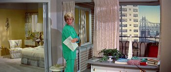 Movie still from “Pillow Talk” (1959), directed by Michael Gordon – A woman in a green suit standing in front of a window; Medium shot, Low angle