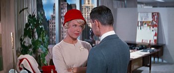 Movie still from “Pillow Talk” (1959), directed by Michael Gordon – A woman wearing a red hat talking to a man in a suit; Medium shot, Over the shoulder angle